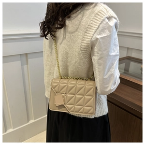 Dettaglio borsa a tracolla trapuntata beige con catena dorata e cuciture geometriche