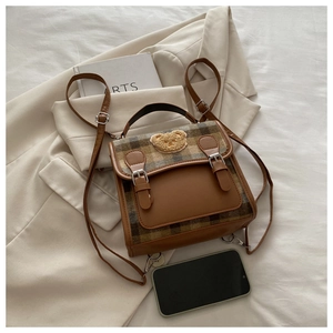 Detail of vintage plaid mini backpack with plush bear badge on white blazer backdrop