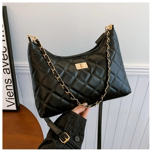 Detailed view of black quilted faux leather handbag with golden chain and twist lock