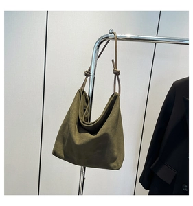 Detail of dark green suede tote bag showing soft drape and stylish knot shoulder strap