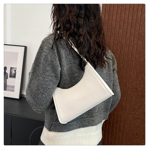 Minimalist white half-moon hobo bag styled as a shoulder bag on a model in a modern room