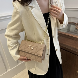 Sac à bandoulière matelassé beige avec fermoir papillon doré et chaîne en métal