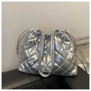 Silver quilted tote bag featuring a metallic finish with a small metal bow detail
