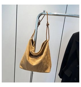 Detailed view of camel suede tote bag showing soft texture and thin knotted shoulder strap