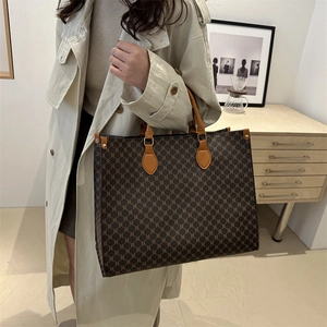 Grand cabas monogramme vintage avec poignées en cuir marron porté par un mannequin
