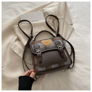 Detail of plaid backpack with brown leather flap and cute bear patch accessory
