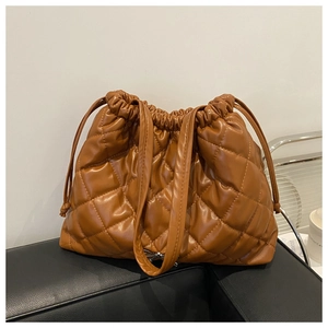 Close-up of quilted caramel bucket bag featuring drawstring closure and silver bow detail