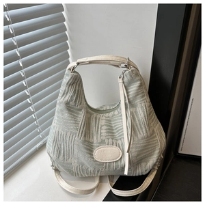 Detail of light green woven tote bag featuring white leather handles and fashion tag