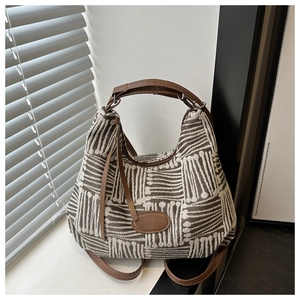 Detail view of woven brown and white plaid tote bag with leather straps and logo patch