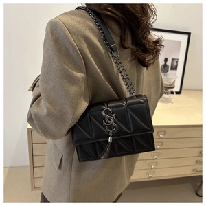 Detail of black quilted leather shoulder bag with metallic chain and long tassel charm