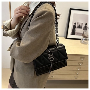 Detail of black quilted leather shoulder bag with silver metal SS logo and tassel chain