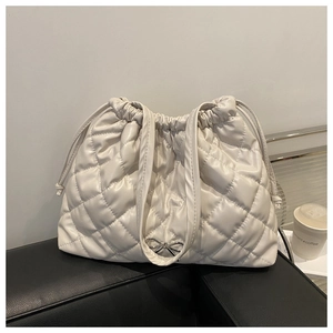 Detail of white quilted tote bag featuring a silver bow accent and drawstring closure