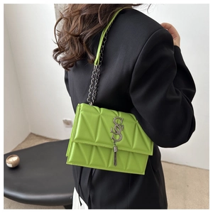 Detail of neon green quilted chain bag with silver S logo and fringe on black blazer