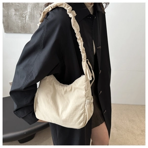 Detail of beige pleated nylon tote bag showing cloud-style strap texture and soft fabric