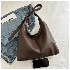 Deep brown oversized shoulder bag with leather texture in a casual lifestyle setting