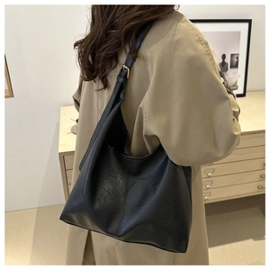 Detail view of a vintage black hobo tote bag featuring textured leather and metal buckles