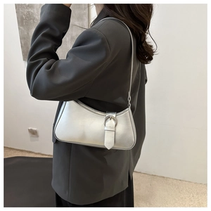 Detail view of silver crescent bag with buckle strap on gray blazer outfit