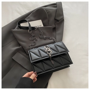 Close-up of black geometric quilted crossbody bag with silver S-buckle and metal tassel