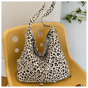 Detail of a large leopard print canvas tote bag resting on a designer yellow chair
