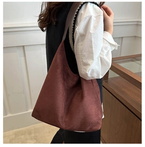 Detail view of large brown suede hobo tote bag worn over the shoulder by a model