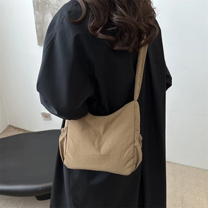 Fashionable khaki nylon tote bag with pleated design worn by model for casual commuting