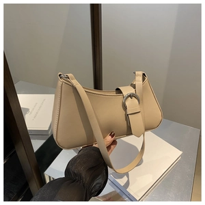 Detail view of beige leather shoulder bag featuring a decorative silver metal buckle closure