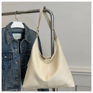 Detail of minimalist cream shoulder bag with lychee texture grain leather on a metal hanger