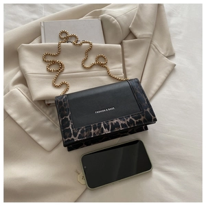 Détail du sac à bandoulière contrasté léopard avec chaîne dorée sur un blazer beige