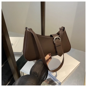 Detailed close-up of dark brown leather tote bag with silver metal round buckle accent