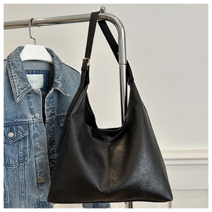 Detail view of a black leather hobo bag with gold buckle on a metal display stand