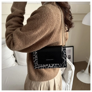 Détail d'un sac à bandoulière élégant avec bords léopard et bandoulière chaîne dorée