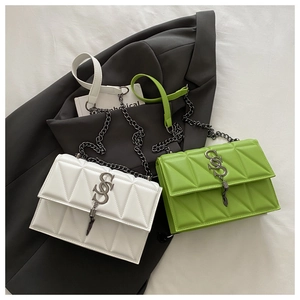 Detail of geometric quilted texture on crossbody bag with metal chain and logo