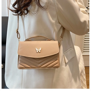 Détail du sac bandoulière beige avec boucle papillon et coutures élégantes en V