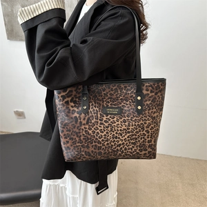 Große Shopper-Tasche mit Leopardenmuster und schwarzen Lederriemen an einem Model in Schwarz