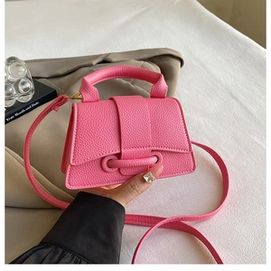 Detail of hot pink litchi grain leather mini trapezoid handbag with structured top handle