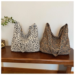 Detail of leopard print canvas tote bags in white and brown on a wooden bench