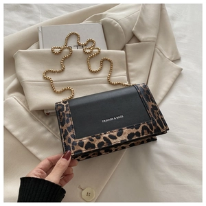 Détail du sac à bandoulière avec imprimé léopard, cuir noir et chaîne dorée chic