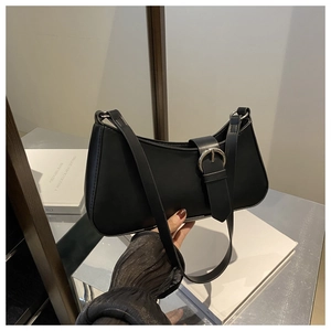 Detail of black matte leather baguette bag featuring silver round buckle and strap