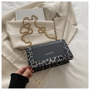 Détail du sac à main léopard avec bandoulière dorée posé sur un blazer beige chic