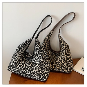 Detail of large leopard print tote bags in black-white and brown tones with leather handles
