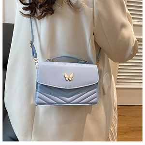 Détail du sac matelassé bleu clair avec fermoir papillon doré et texture en cuir