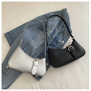 Detail of silver and black crescent baguette bags with metal buckles on denim fabric