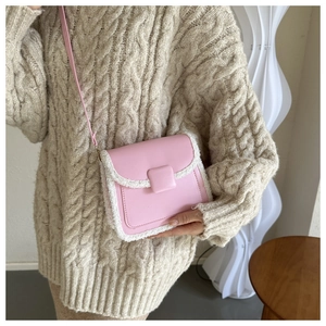 Detailed view of pink leather crossbody bag with white faux shearling trim and flap cover