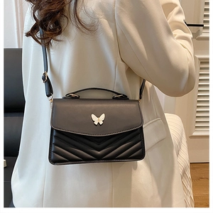 Détail du sac bandoulière noir en similicuir avec boucle papillon et coutures en V élégantes
