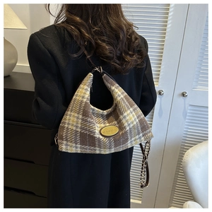 Gros plan d'un sac à main en laine à carreaux vintage avec boucle dorée et chaîne