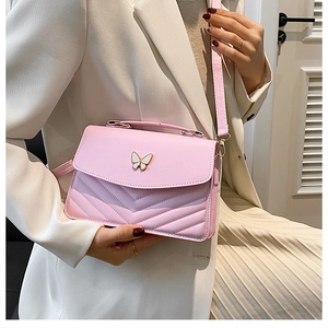 Détail du sac bandoulière rose avec texture matelassée en V et fermoir papillon blanc