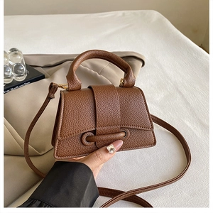 Detail of a brown lychee-textured mini handbag with a round handle and ring hardware