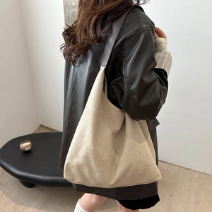 Minimalist beige suede tote bag with contrast brown strap shown on a model