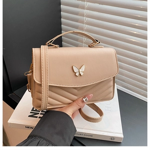 Détail du petit sac bandoulière beige en simili cuir surpiqué avec fermoir papillon