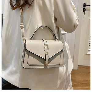 Model wearing a minimalist cream leather crossbody bag with decorative metal buckle